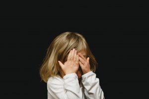 Un enfant se cachant les yeux, illustrant un article sur les poux.