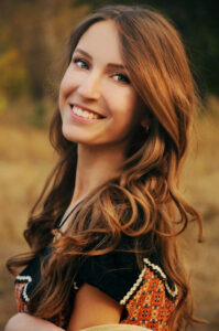 Jeune femme mignonne aux longs cheveux auburn souriant dans le champ d'automne.